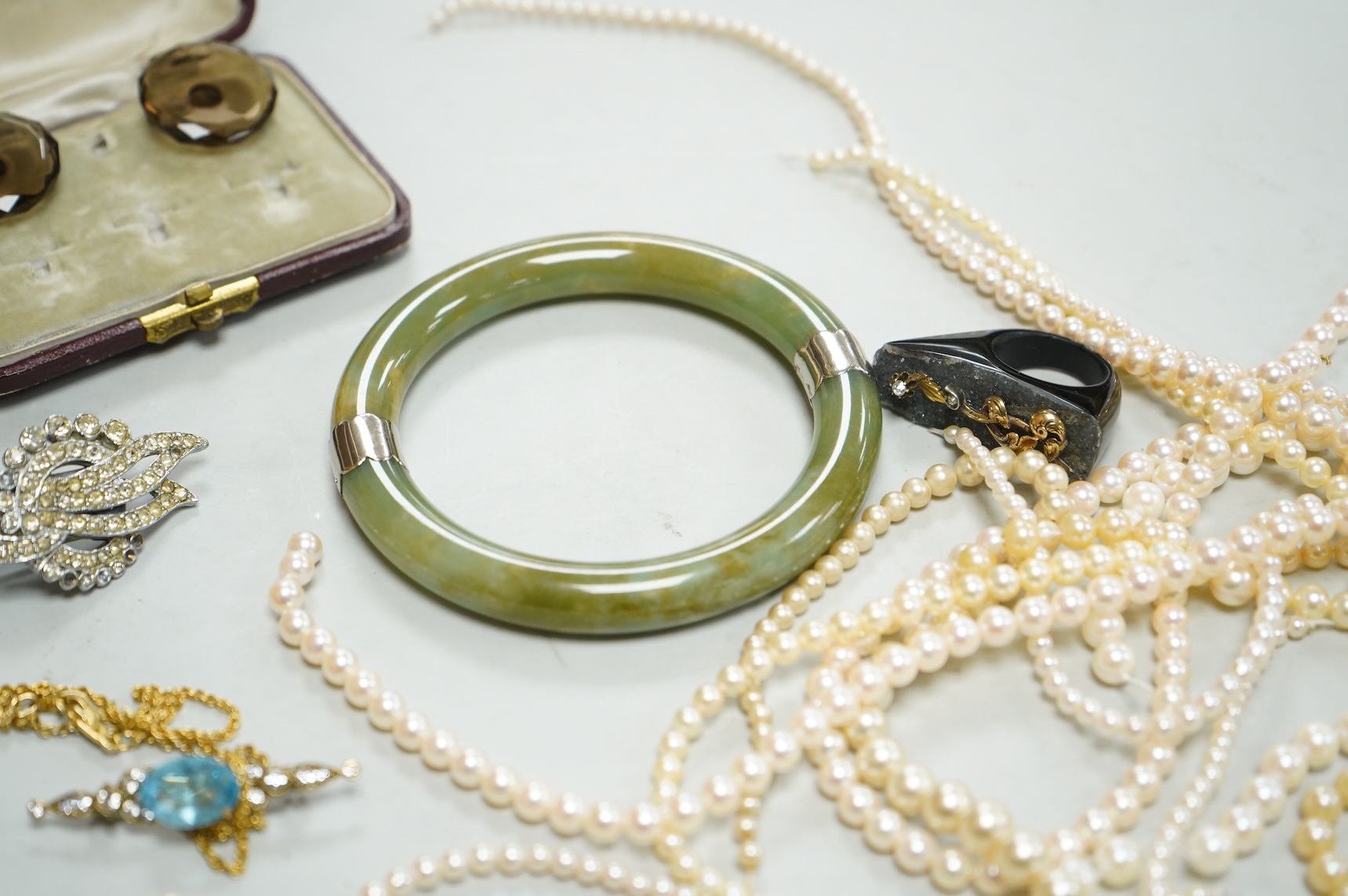 A collection of assorted jewellery including a jade bangle, cultured pearl necklaces and a diamond set yellow metal and quartz ring.